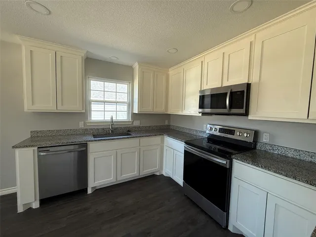 a kitchen with stainless steel appliances granite countertop a stove a sink and a microwave