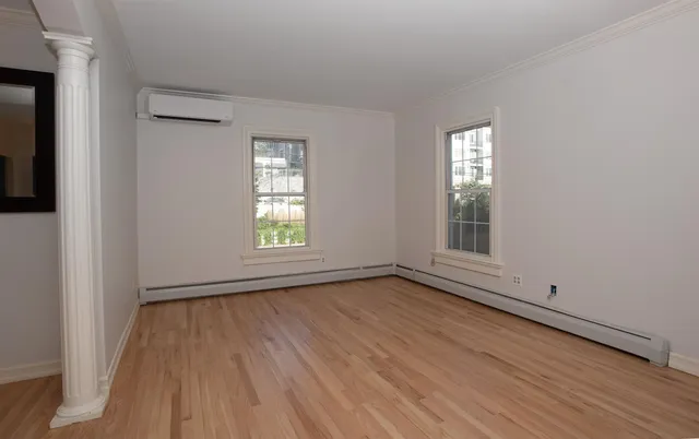 a view of an empty room with wooden floor and a window