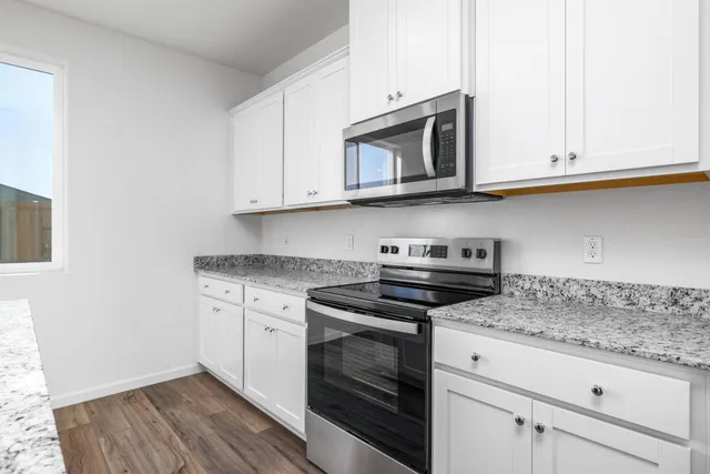 a kitchen with granite countertop white cabinets and stainless steel appliances