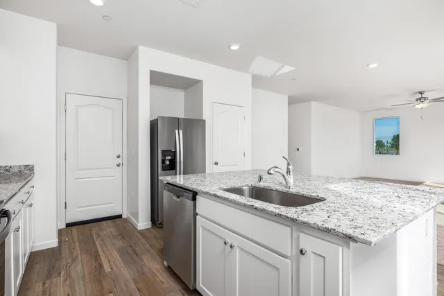 a kitchen with granite countertop a sink and refrigerator