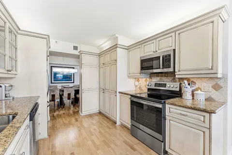 a kitchen with stainless steel appliances a stove top oven a sink a dining table and chairs with wooden floor