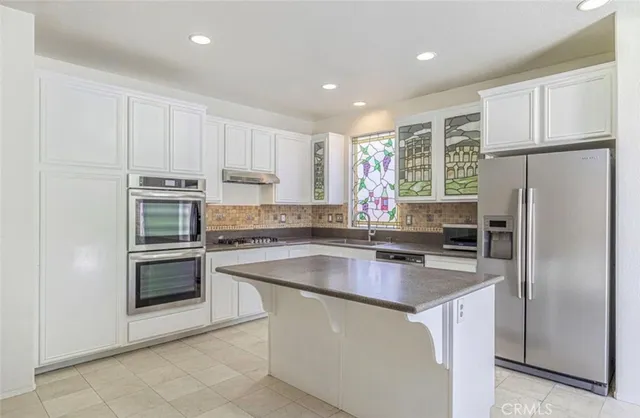 a kitchen with stainless steel appliances granite countertop a refrigerator sink and stove