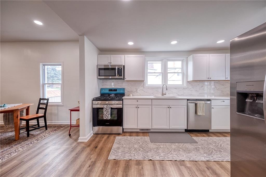 1415 Pacific Avenue Monaca, PA 15061 - Photo 25 of 39 a kitchen with granite countertop a stove top oven a sink dishwasher a dining table and chairs with wooden floor