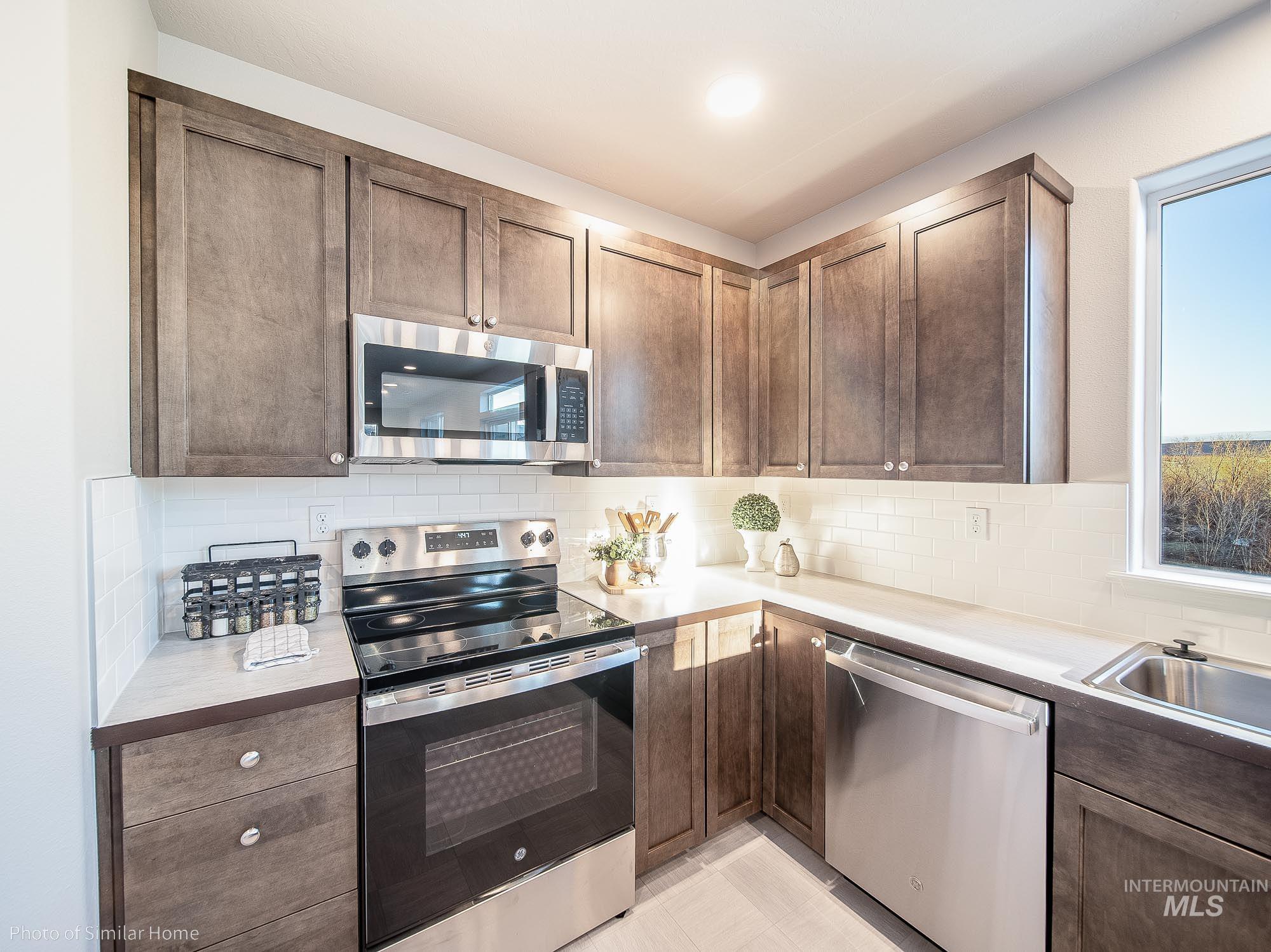 2049 Sumac Avenue Middleton, ID 83644 - Photo 4 of 6 Kitchen with stainless steel appliances, tasteful backsplash, and dark brown cabinetry