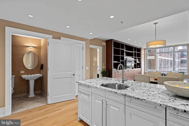 a kitchen with a sink dishwasher a dining table and chairs with wooden floor