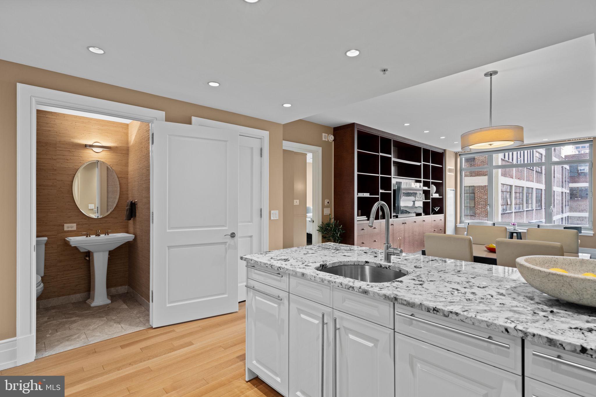 130 South 18th Street, Unit 503 Philadelphia, PA 19103 - Photo 6 of 43 a kitchen with a sink dishwasher a dining table and chairs with wooden floor