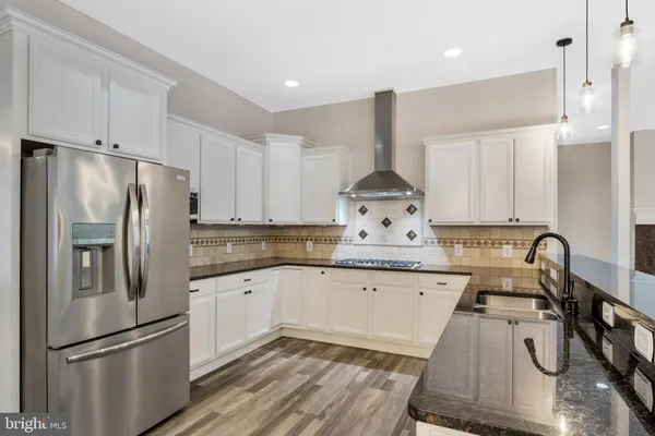 a large kitchen with stainless steel appliances granite countertop a large counter top and a wooden floors