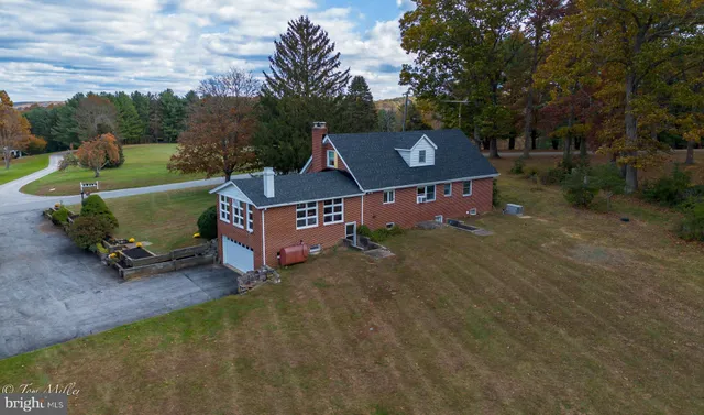 an aerial view of a house with a yard and trees all around