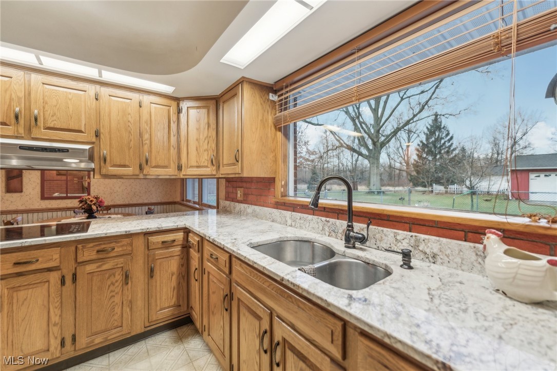 6326 Murray Ridge Road Elyria, OH 44035 - Photo 16 of 49 Kitchen with black electric cooktop, light stone countertops, sink, and range hood