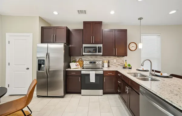a kitchen with stainless steel appliances granite countertop a refrigerator a sink a stove a microwave and island