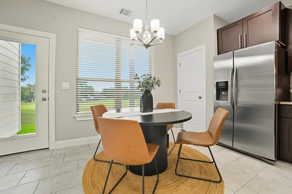 a kitchen with stainless steel appliances granite countertop a stove a refrigerator a sink a dining table and chairs