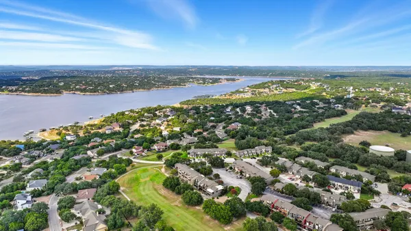 an aerial view of residential houses with outdoor space and lake view