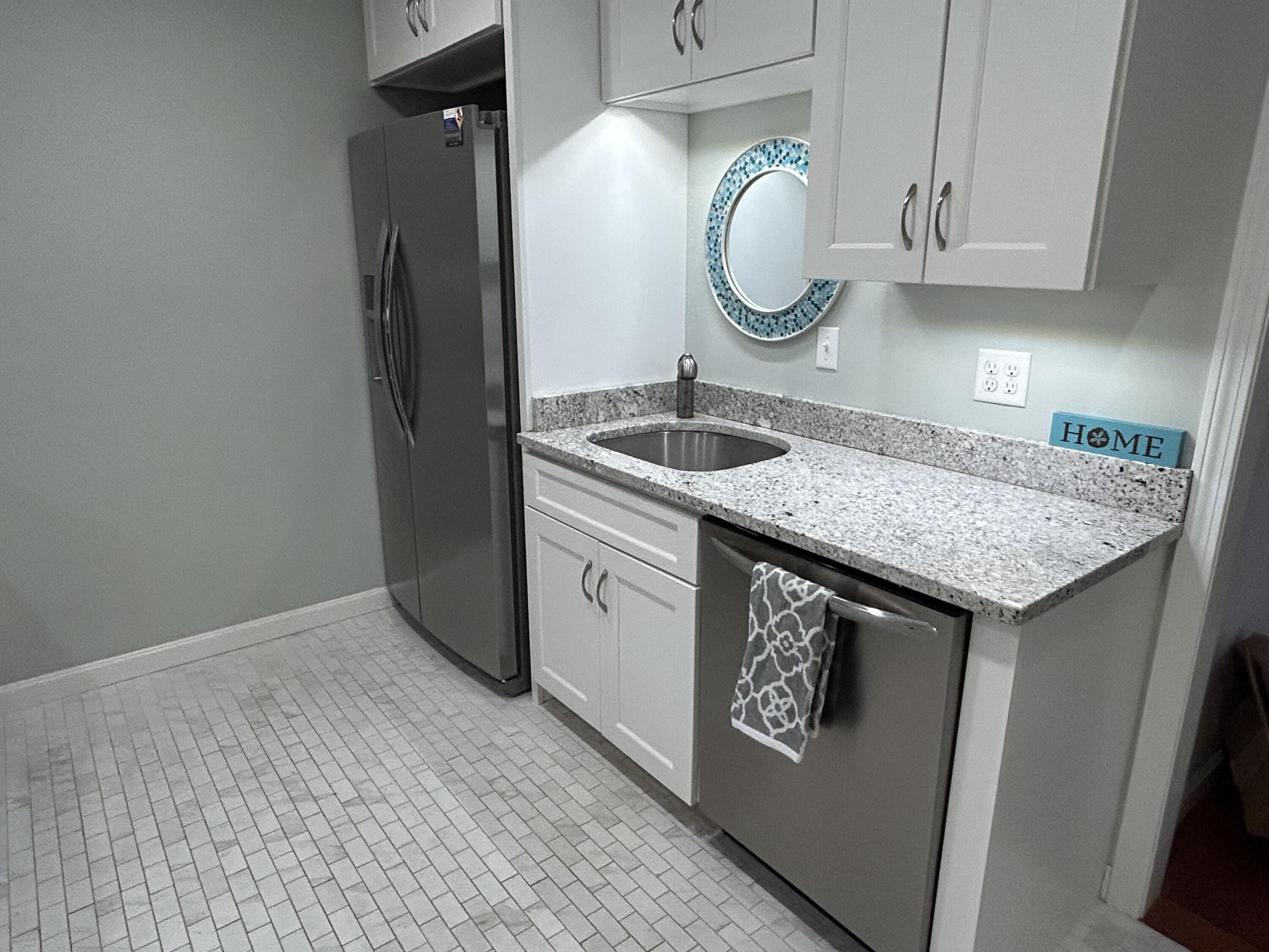 59 Main Street, Unit 192 Dennis, MA 02638 - Photo 14 of 44 a kitchen with a granite countertop sink a refrigerator and a wooden cabinets