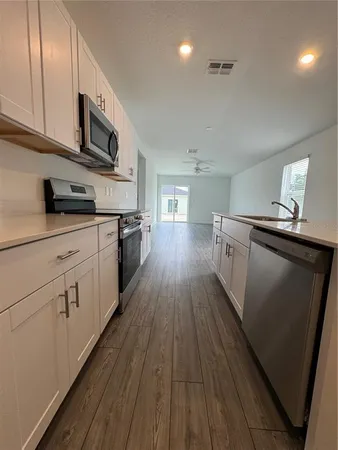 a kitchen with stainless steel appliances granite countertop wooden floors and white cabinets
