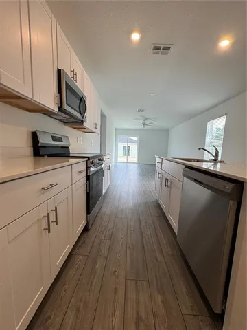 a kitchen with stainless steel appliances granite countertop wooden floors and white cabinets