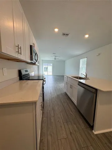 a kitchen with cabinets wooden floor and stainless steel appliances