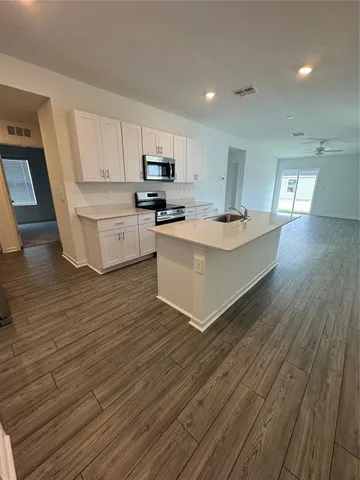 a living room with stainless steel appliances a kitchen island hardwood floor sink and stove