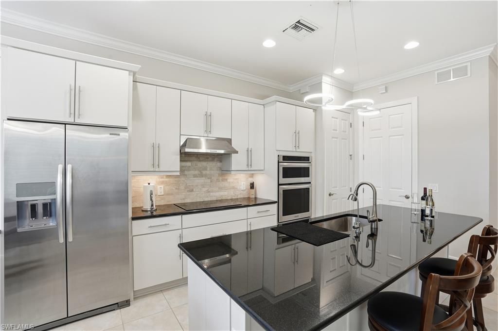 9328 Fieldstone Lane Naples, FL 34120 - Photo 11 of 40 a kitchen with kitchen island a counter top space appliances and cabinets