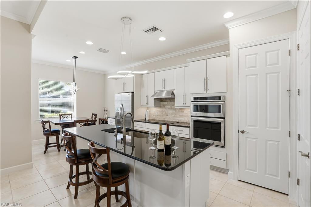 9328 Fieldstone Lane Naples, FL 34120 - Photo 9 of 40 a kitchen with stainless steel appliances kitchen island granite countertop a sink and cabinets