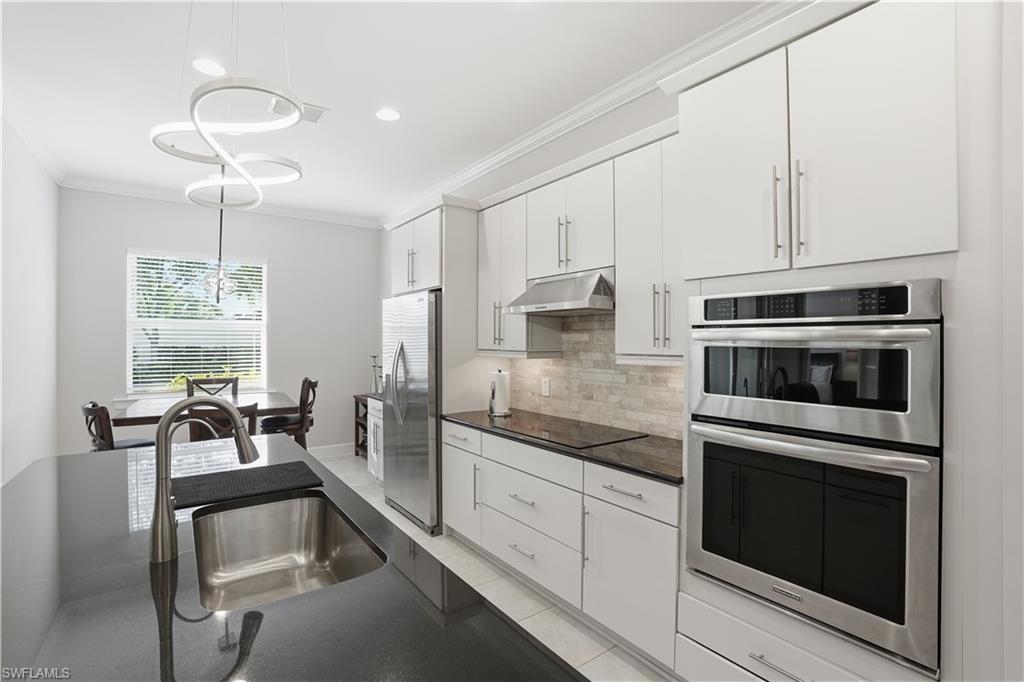 9328 Fieldstone Lane Naples, FL 34120 - Photo 10 of 40 a kitchen with granite countertop white cabinets and stainless steel appliances