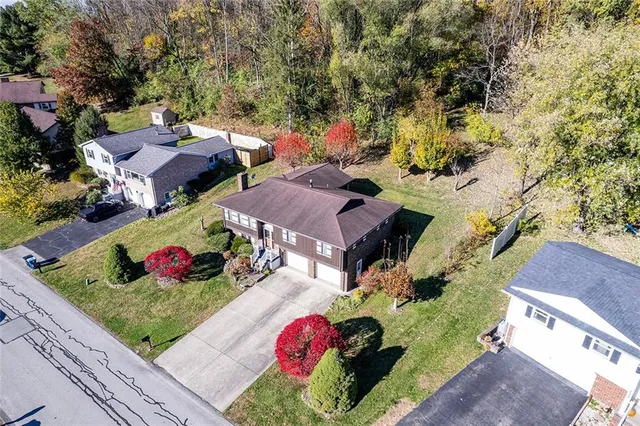 an aerial view of a house with a yard and a large tree