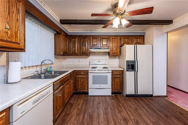 a kitchen with stainless steel appliances a stove a sink dishwasher and a refrigerator with wooden floor