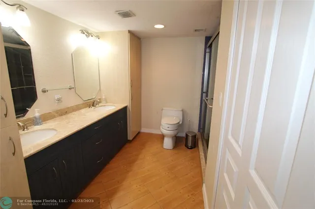 a bathroom with a double vanity sink toilet and mirror