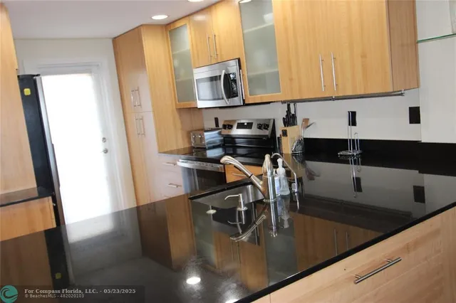 a kitchen with stainless steel appliances granite countertop a sink a stove and a microwave