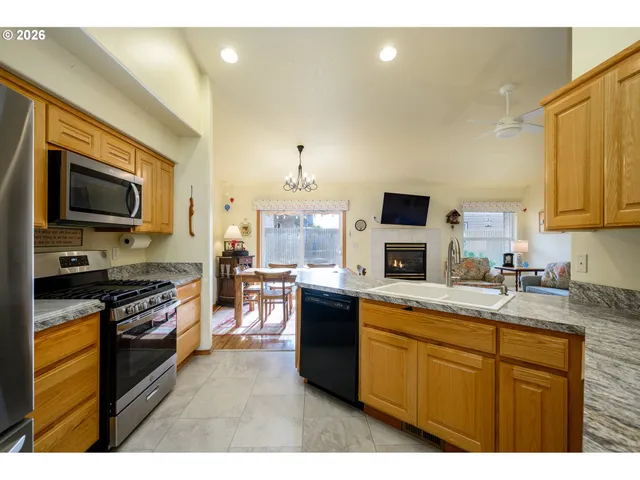 a kitchen with stainless steel appliances granite countertop a stove top oven a sink dishwasher a dining table and chairs with wooden floor