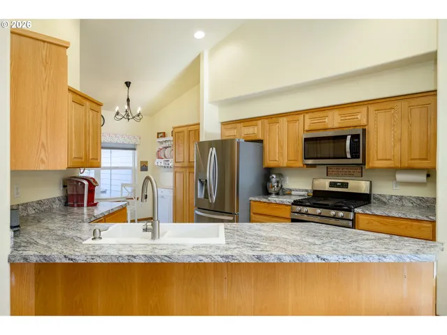 a kitchen with stainless steel appliances granite countertop a sink a stove top oven a granite counter tops and a view of living room