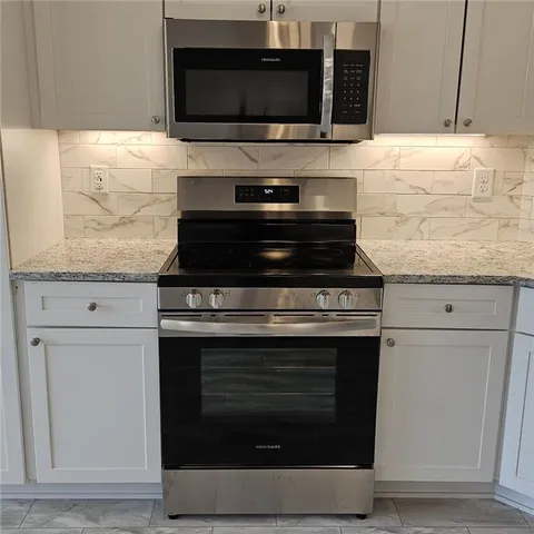 a kitchen with granite countertop a stove and a microwave