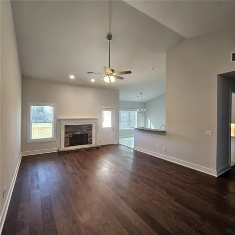 a view of an empty room with wooden floor fireplace and a window
