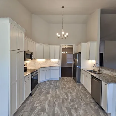 a large kitchen with stainless steel appliances granite countertop a sink refrigerator and cabinets