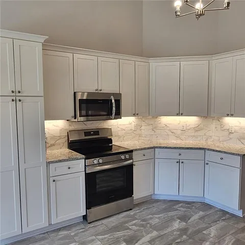 a kitchen with granite countertop white cabinets and stainless steel appliances