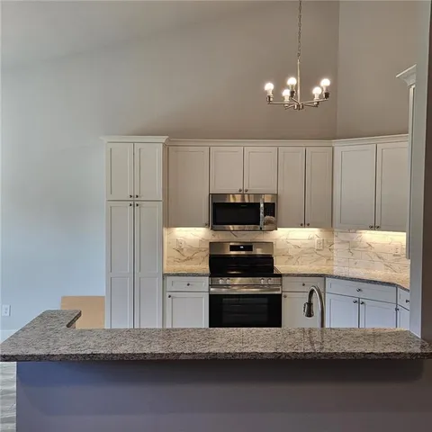 a kitchen with granite countertop a stove a sink and a refrigerator