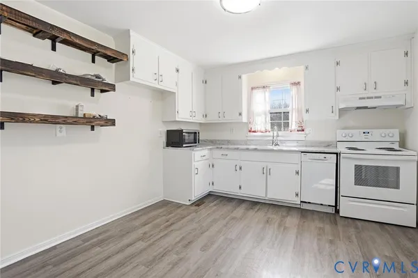 a kitchen with a white cabinets and wooden floor