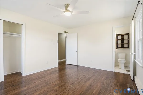 an empty room with wooden floor and a ceiling fan