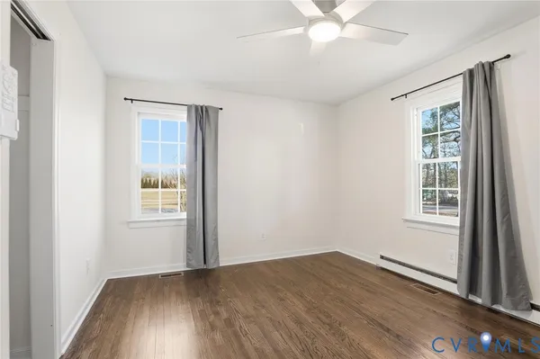 an empty room with wooden floor fan and windows
