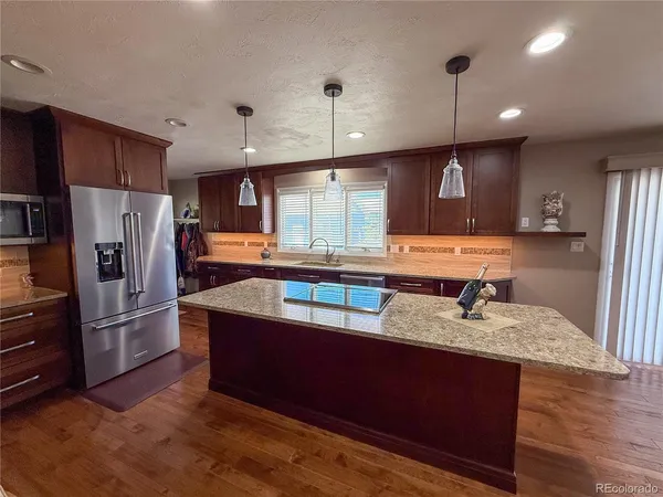 a kitchen with stainless steel appliances granite countertop a refrigerator a sink dishwasher a stove and a refrigerator