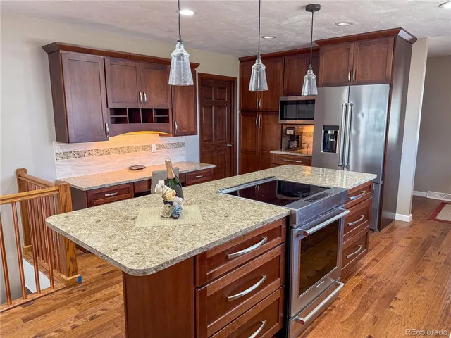 a kitchen with stainless steel appliances granite countertop a sink a stove a refrigerator and island