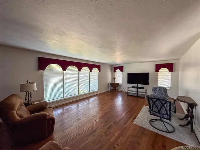 a living room with furniture a flat screen tv and a large window