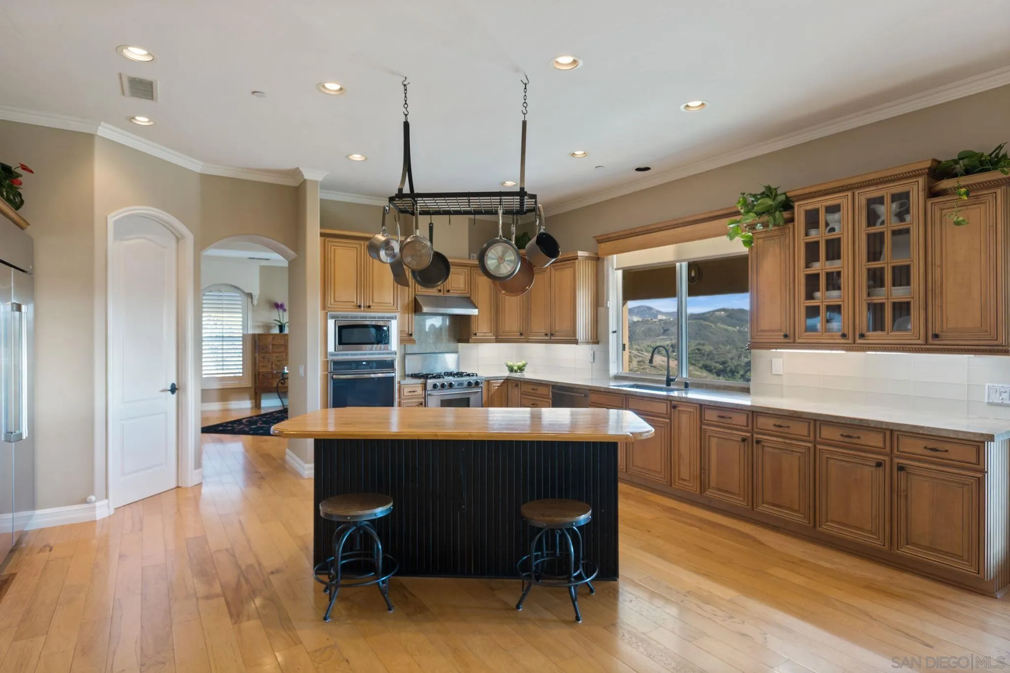 30419 Canyon Estates Road Vista, CA 92084 - Photo 20 of 75 a dining hall with stainless steel appliances kitchen island granite countertop a table chairs and a refrigerator