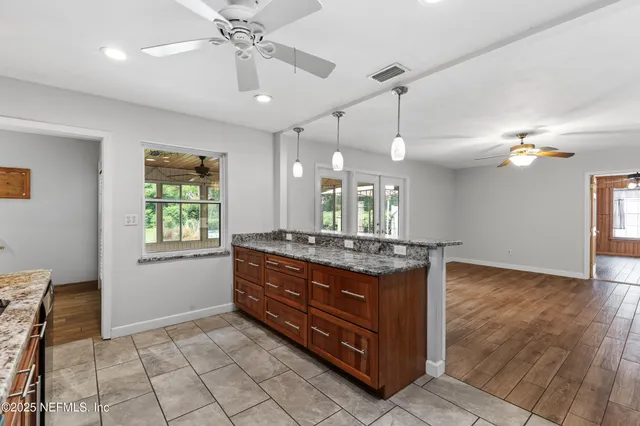 a room with kitchen island stainless steel appliances chandelier and window