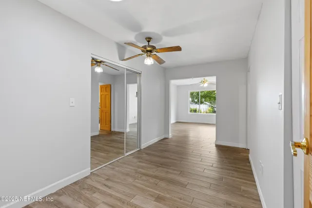 a view of an empty room with window and wooden floor