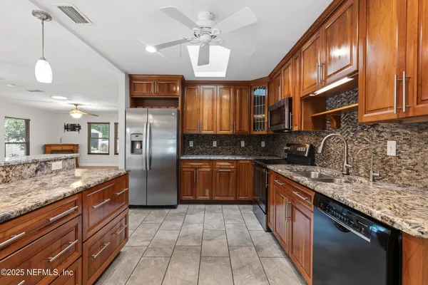 a kitchen with stainless steel appliances granite countertop a sink a stove top oven a refrigerator cabinets and wooden floor