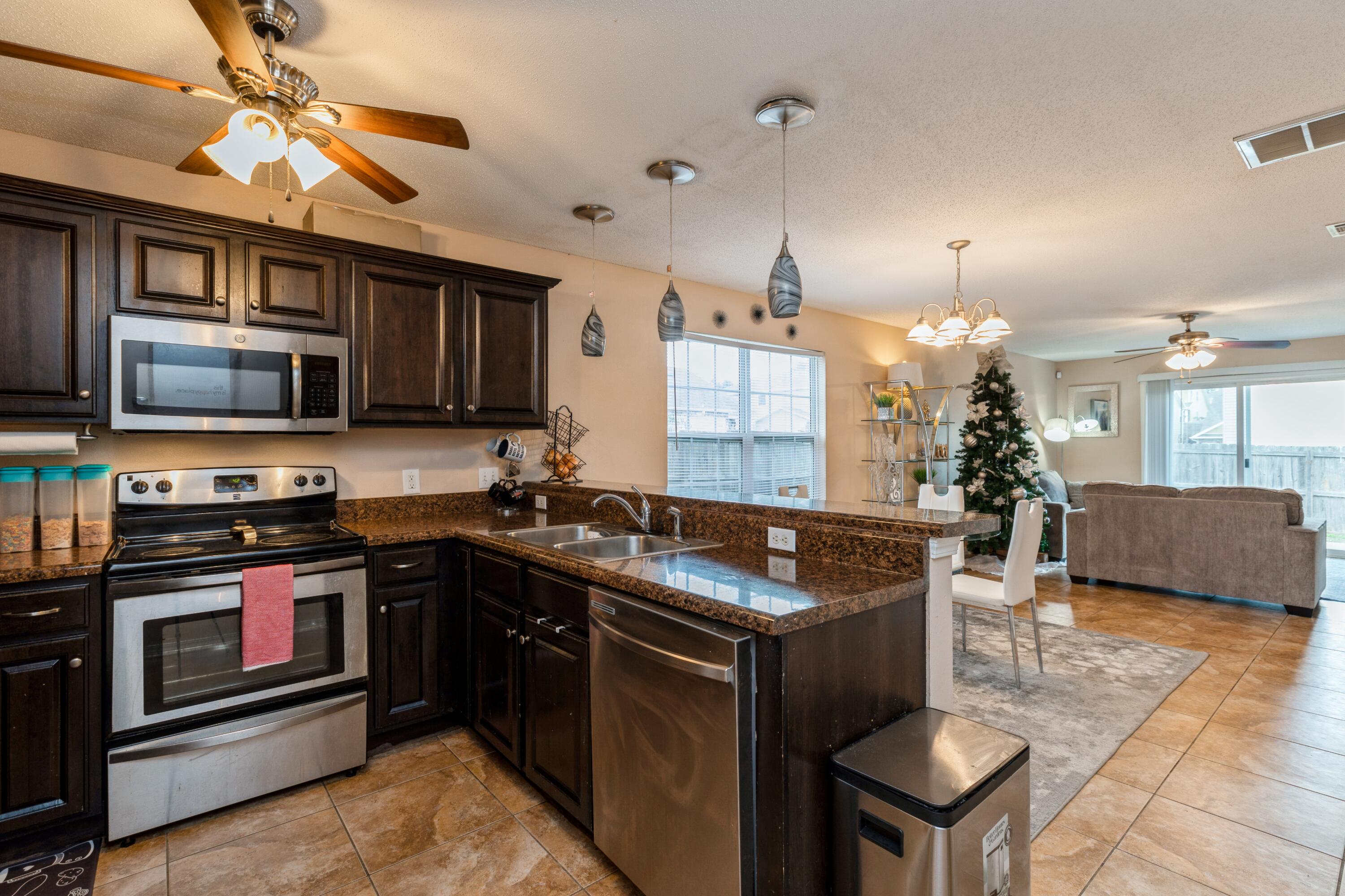 200 Wainwright Drive Crestview, FL 32539 - Photo 5 of 17 a kitchen with kitchen island granite countertop a stove top oven a sink a dining table and chairs with wooden floor