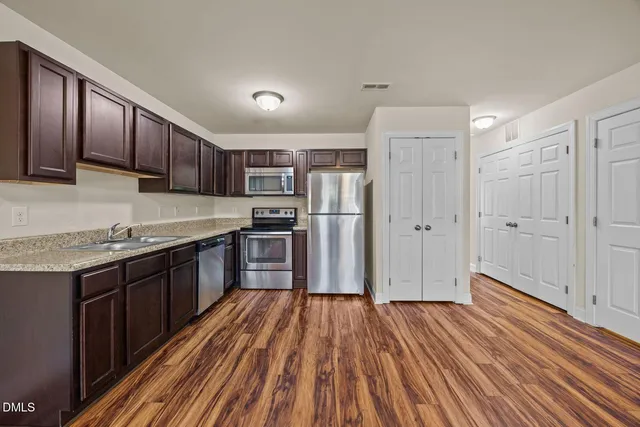 a kitchen with wooden floors stainless steel appliances a sink and cabinets