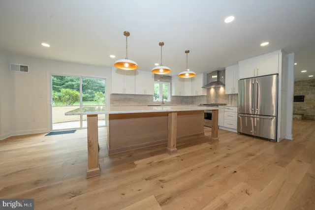 a kitchen with kitchen island a stove a refrigerator wooden floor and a view of living room