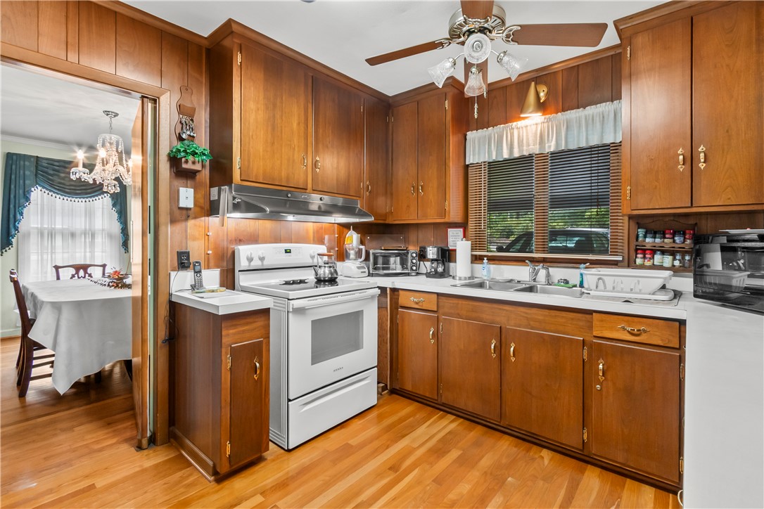 118 Blair Road Belton, SC 29627 - Photo 29 of 49 Warm wood cabinetry and matching wall paneling highlight this retro kitchen featuring durable hardwood flooring.