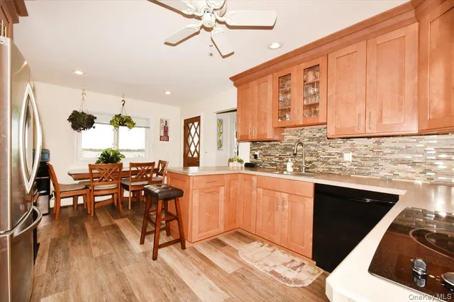 a kitchen with stainless steel appliances granite countertop a refrigerator a sink dishwasher a stove and white countertops with wooden floor